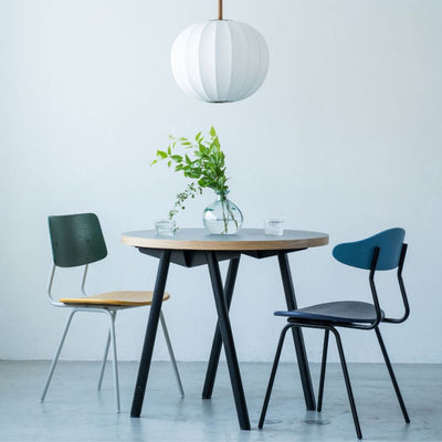 A modern dining table with three chairs and a pendant light above.