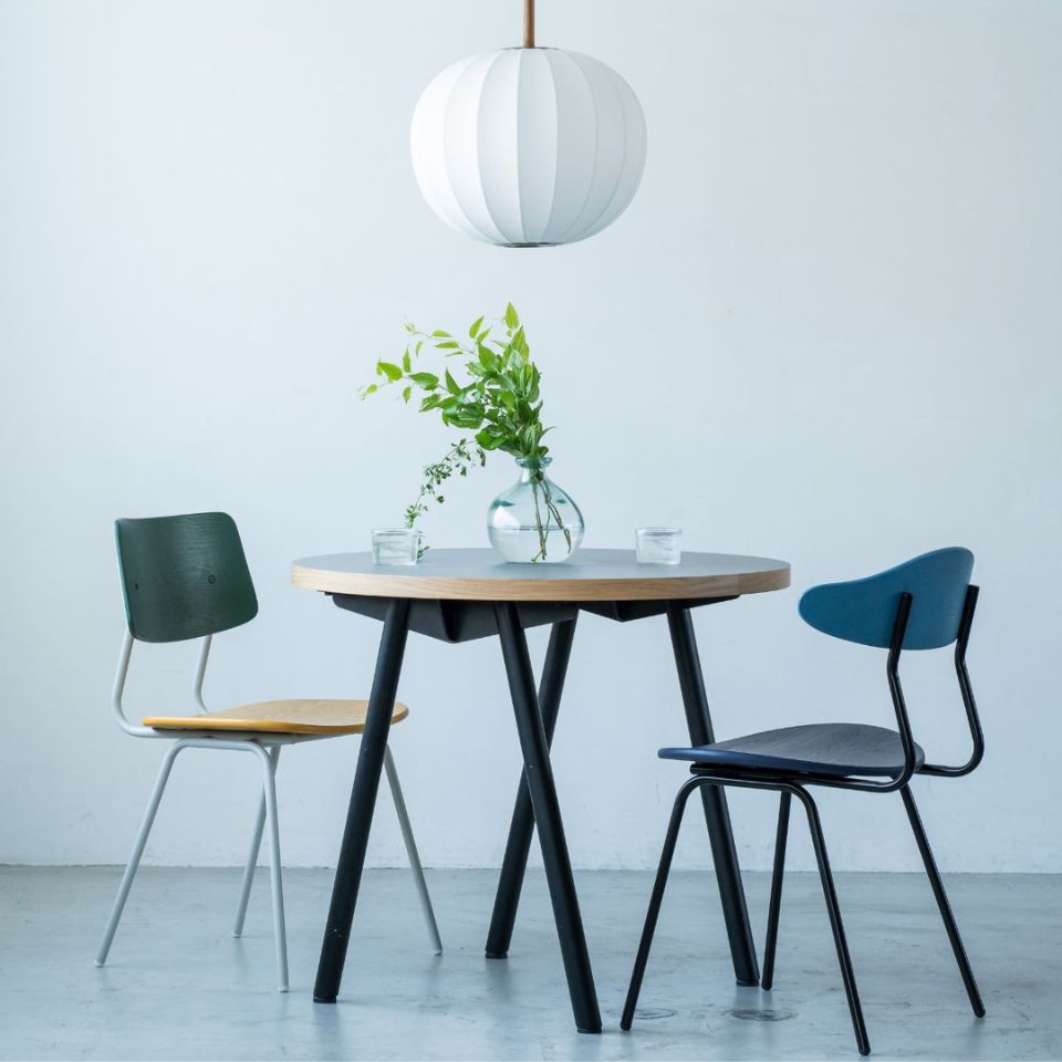 A modern dining table with three chairs and a pendant light above.